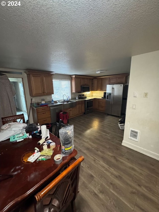 kitchen featuring sink, dark hardwood / wood-style flooring, a textured ceiling, and appliances with stainless steel finishes