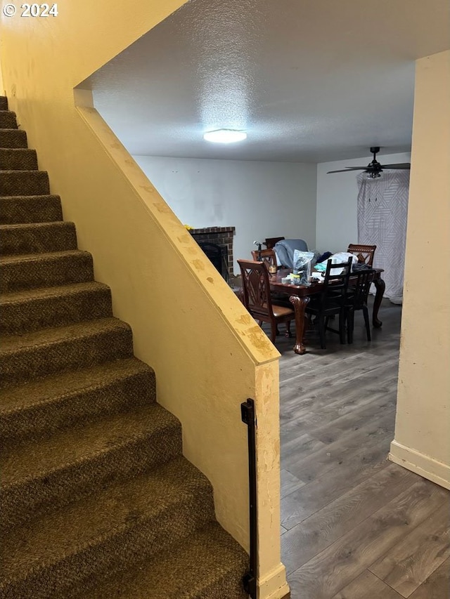 stairway with wood-type flooring, a textured ceiling, and ceiling fan