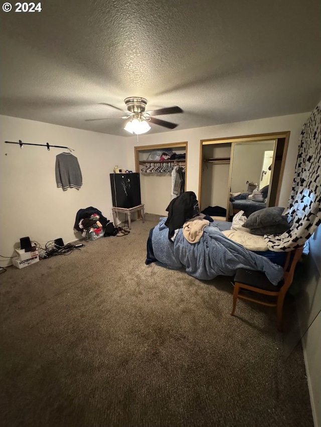 carpeted bedroom featuring multiple closets, ceiling fan, and a textured ceiling