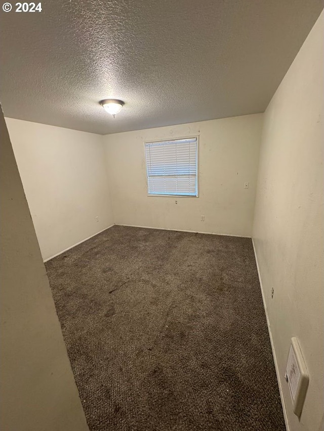 carpeted empty room with a textured ceiling