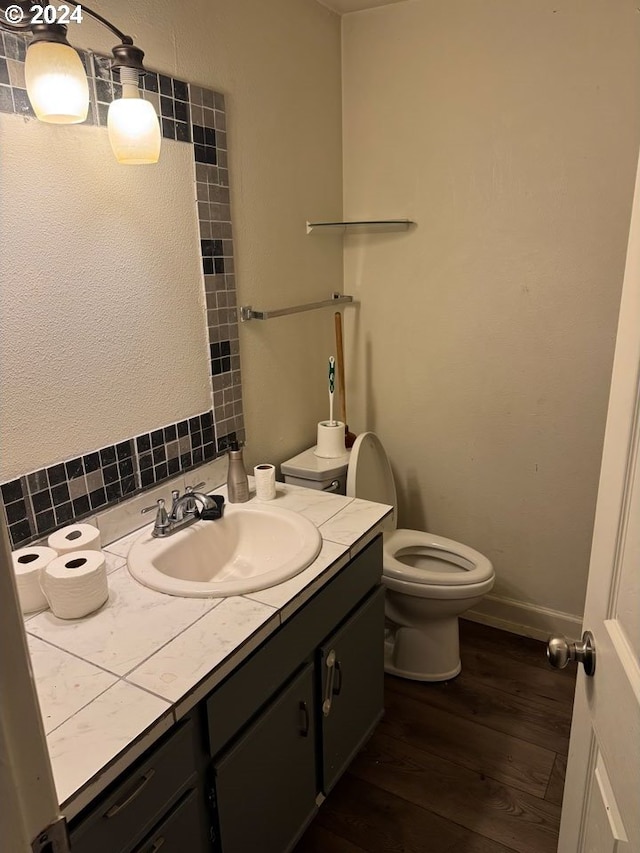 bathroom featuring hardwood / wood-style floors, vanity, toilet, and backsplash