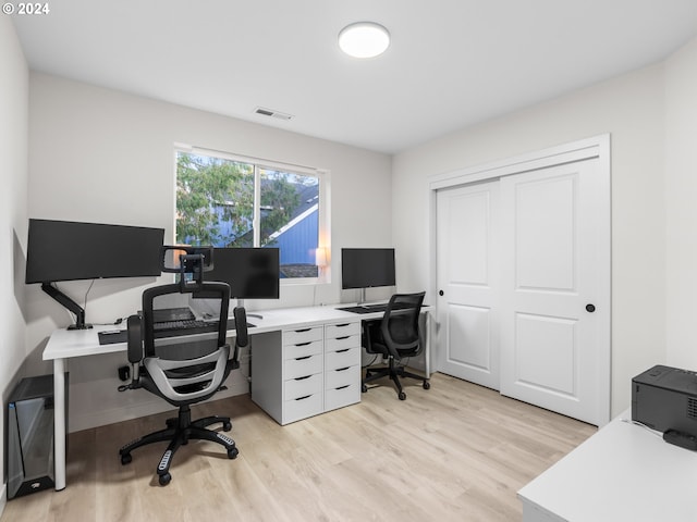 home office with light wood-style flooring and visible vents