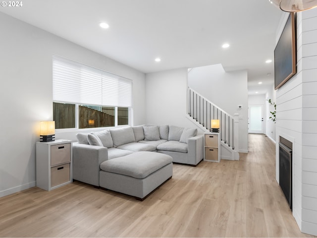 living room with a large fireplace and light hardwood / wood-style flooring