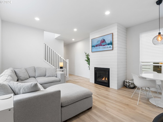 living area with a large fireplace, stairs, light wood-type flooring, and recessed lighting