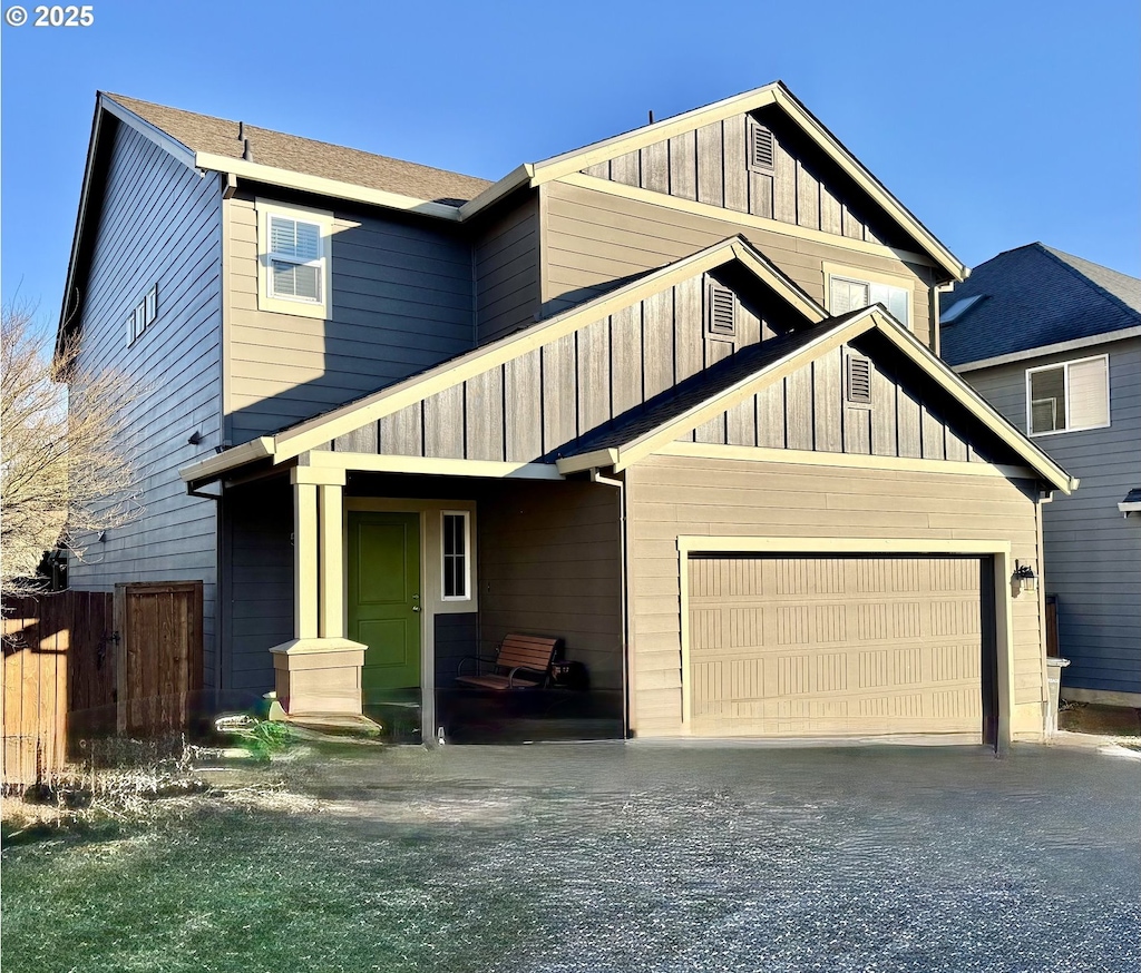 craftsman-style home featuring board and batten siding, driveway, and fence