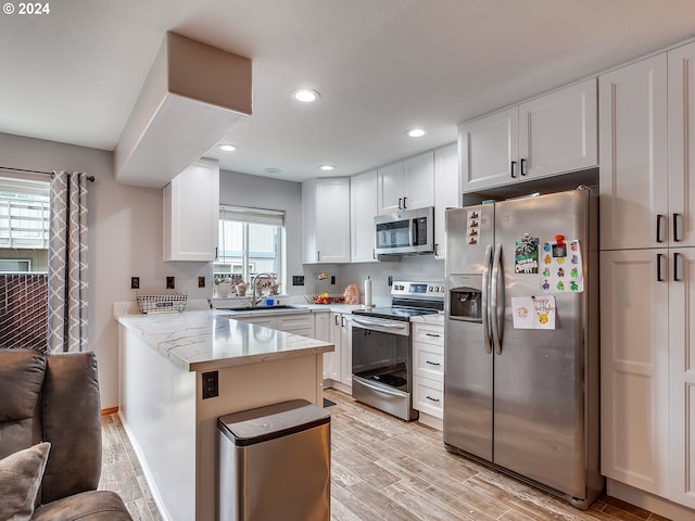 kitchen featuring kitchen peninsula, white cabinets, appliances with stainless steel finishes, and a healthy amount of sunlight