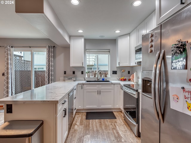 kitchen featuring appliances with stainless steel finishes, light wood-type flooring, kitchen peninsula, and white cabinetry