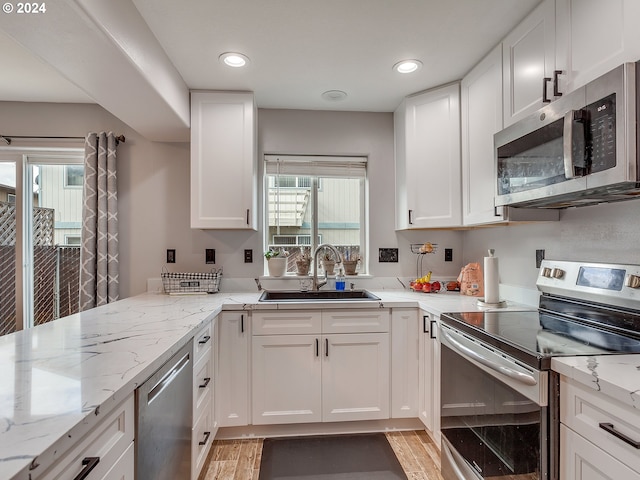 kitchen with a healthy amount of sunlight, appliances with stainless steel finishes, sink, and white cabinetry