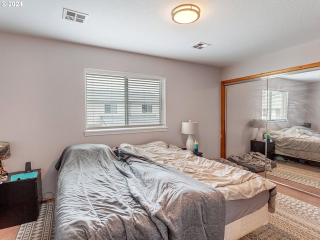 bedroom featuring multiple windows, a closet, and a textured ceiling