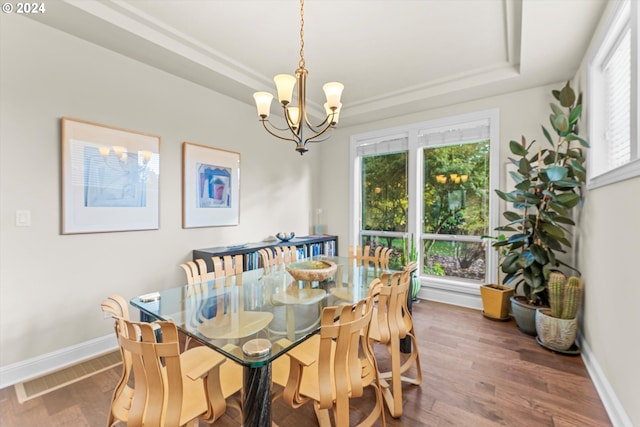 dining space featuring a notable chandelier, dark hardwood / wood-style floors, and a tray ceiling