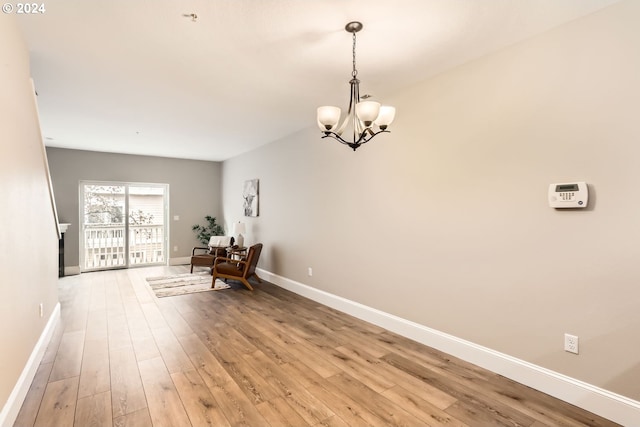 unfurnished room featuring a notable chandelier and light hardwood / wood-style floors