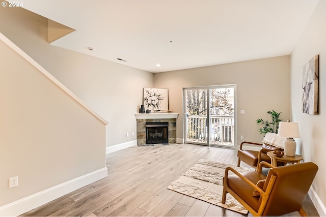 sitting room with light wood-type flooring and a tiled fireplace