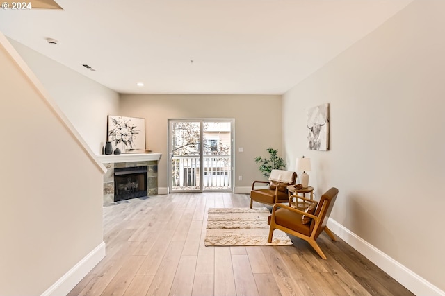 sitting room featuring light hardwood / wood-style floors and a tiled fireplace