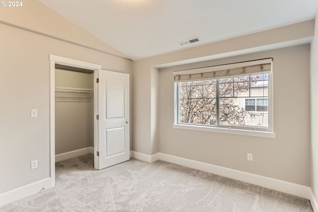 unfurnished bedroom with lofted ceiling, light carpet, and a closet