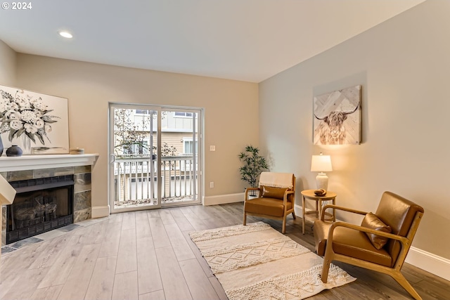 living area with hardwood / wood-style floors and a tiled fireplace