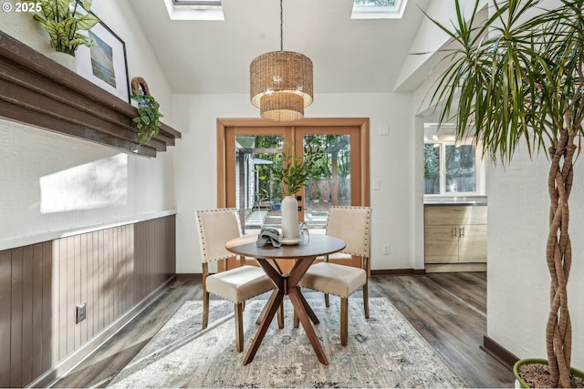 dining area featuring lofted ceiling with skylight and dark hardwood / wood-style flooring