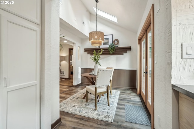 dining area featuring dark wood-type flooring and vaulted ceiling with skylight