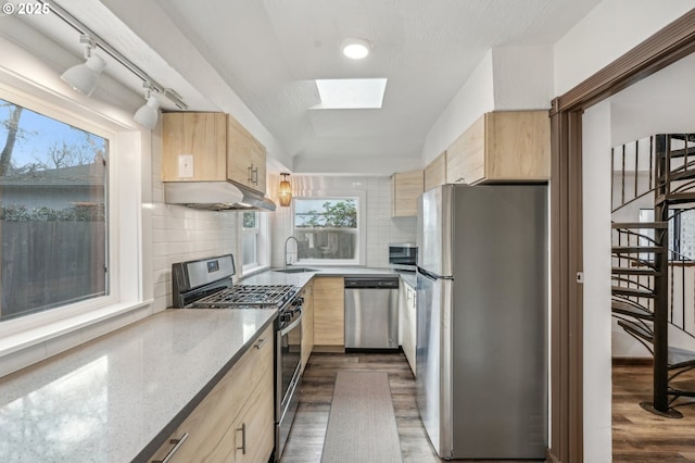 kitchen with light brown cabinets, appliances with stainless steel finishes, backsplash, and light stone counters