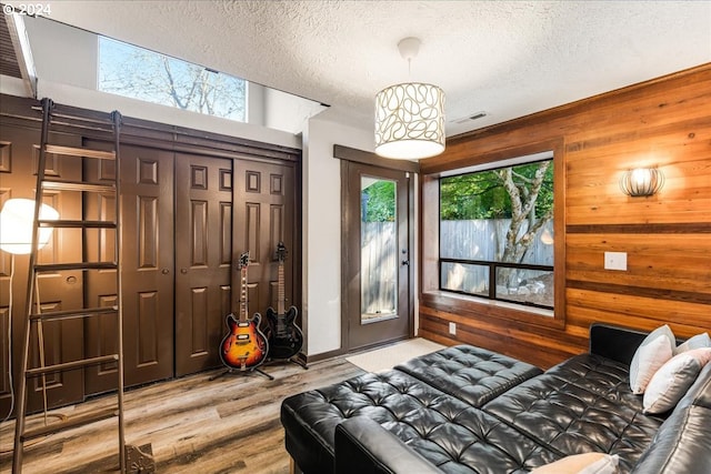 bedroom featuring a textured ceiling, wood walls, and hardwood / wood-style floors