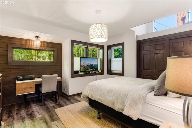 bedroom with dark hardwood / wood-style floors and wood walls