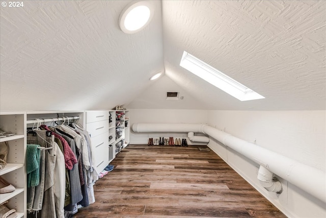 spacious closet with vaulted ceiling with skylight and hardwood / wood-style floors