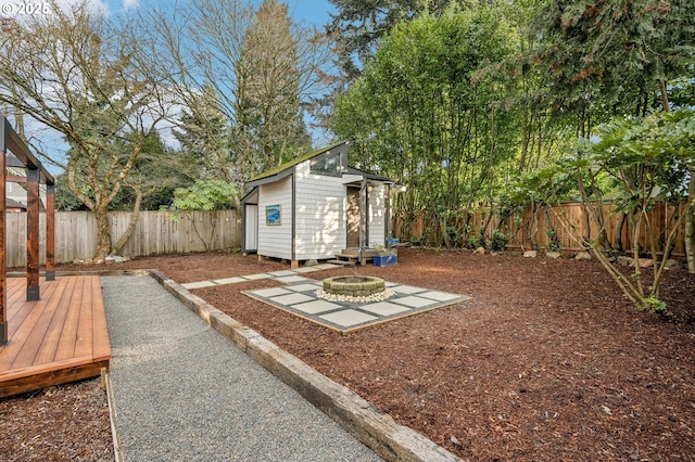 view of yard featuring a deck, an outdoor fire pit, and a storage unit