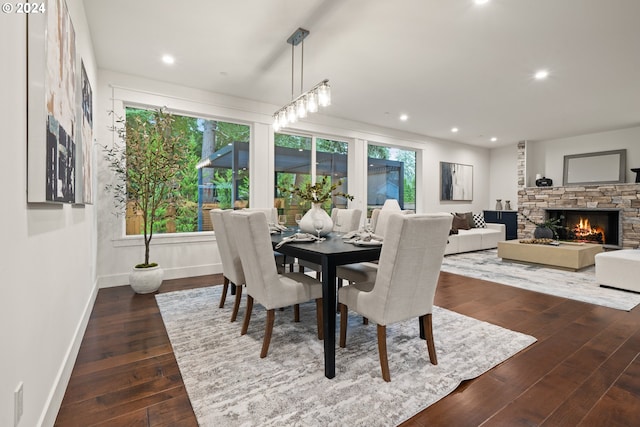 dining area with a stone fireplace and dark wood-type flooring