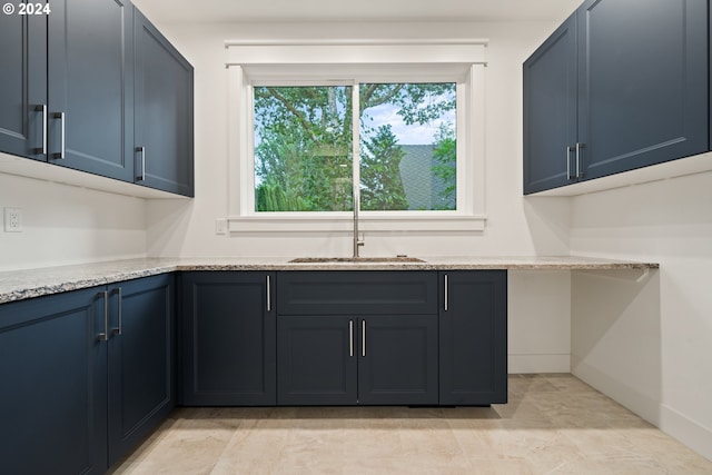 kitchen featuring light stone counters and sink