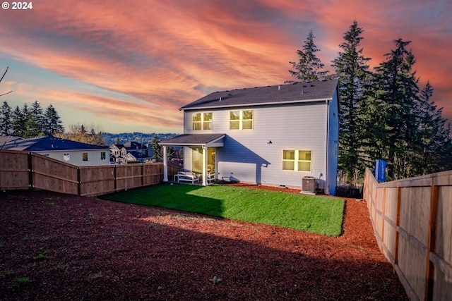 back house at dusk with a lawn and central AC unit