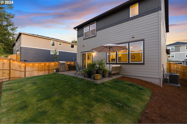 back house at dusk featuring a patio, central air condition unit, and a lawn