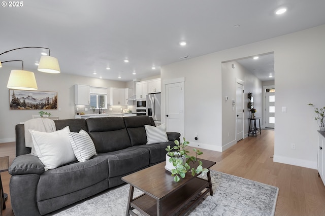 living room featuring sink, a wealth of natural light, and light wood-type flooring