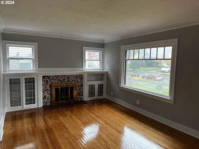 unfurnished living room with wood-type flooring, ornamental molding, and a tile fireplace