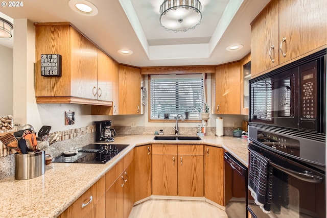 kitchen with black appliances, sink, a raised ceiling, and light stone countertops