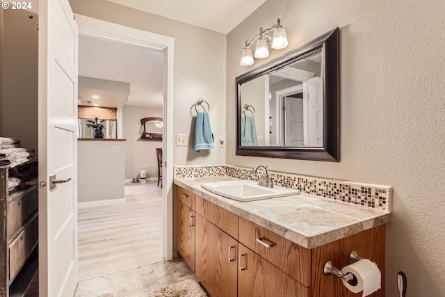 bathroom with hardwood / wood-style floors, vanity, and backsplash