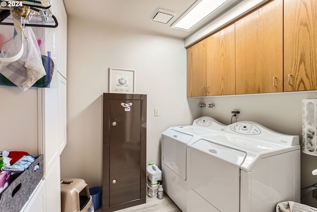 clothes washing area featuring light hardwood / wood-style flooring, cabinets, and independent washer and dryer