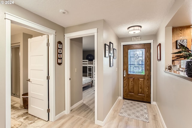 doorway to outside with light hardwood / wood-style floors and a textured ceiling