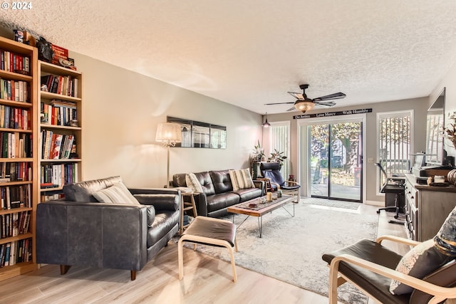 living room with light wood-type flooring, a textured ceiling, and ceiling fan