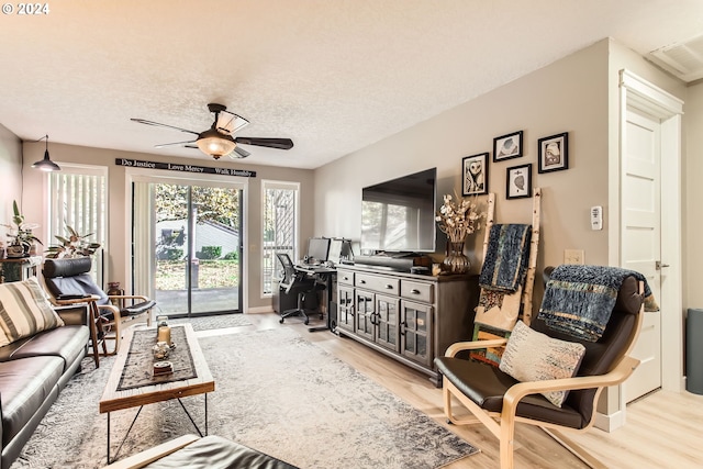 living room with ceiling fan, a textured ceiling, and light hardwood / wood-style floors