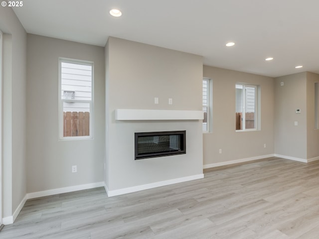 838 NW 178th Way, Ridgefield, WA 98642 - unfurnished living room featuring a glass covered fireplace, light wood-type flooring, recessed lighting, and baseboards