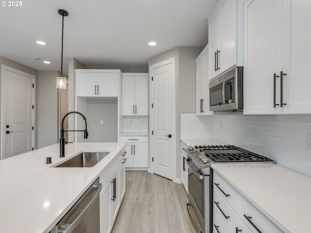 838 NW 178th Way, Ridgefield, WA 98642 - kitchen with stainless steel appliances, a sink, recessed lighting, light wood-style floors, and white cabinets
