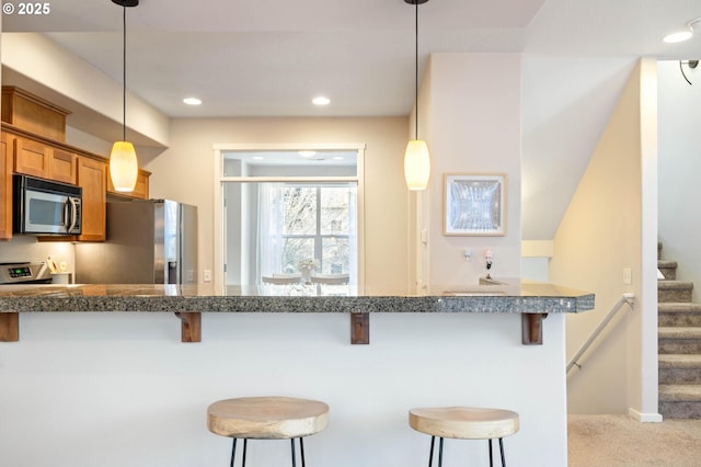 kitchen featuring hanging light fixtures, appliances with stainless steel finishes, and a kitchen bar