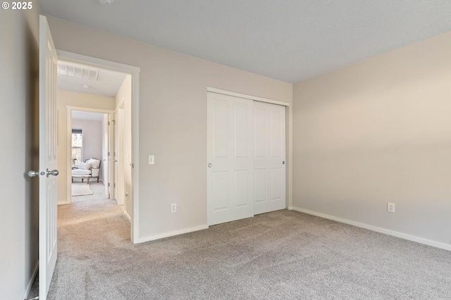 unfurnished bedroom featuring light carpet and a closet