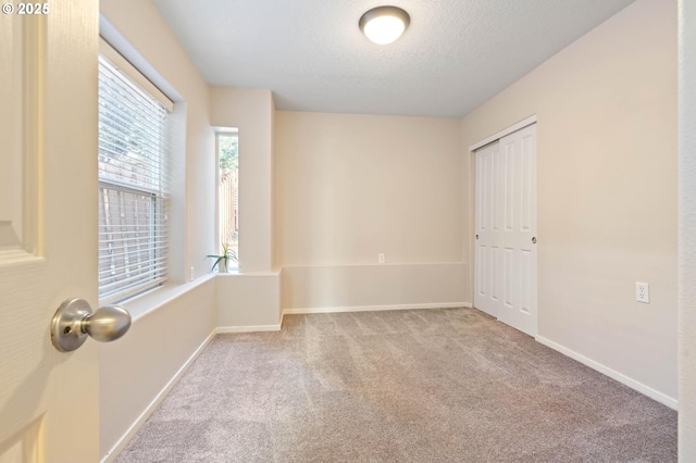 carpeted empty room featuring a textured ceiling