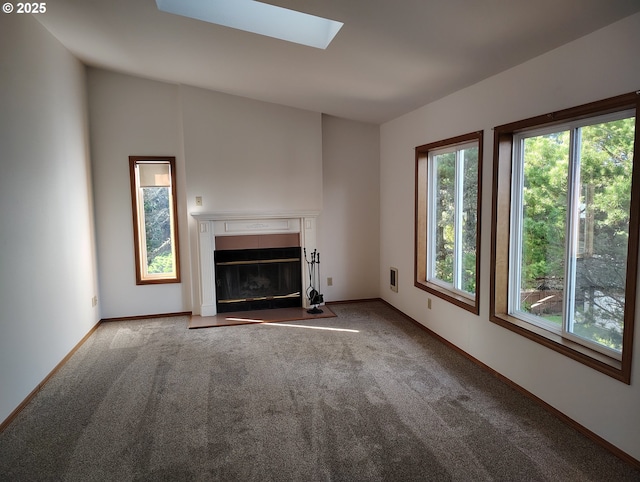 unfurnished living room featuring a fireplace with flush hearth, a skylight, carpet flooring, and baseboards