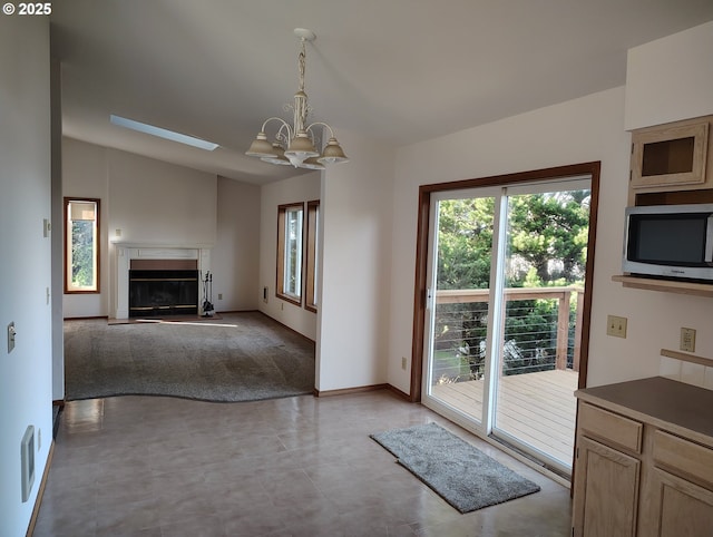 doorway to outside featuring lofted ceiling, a notable chandelier, a premium fireplace, visible vents, and baseboards