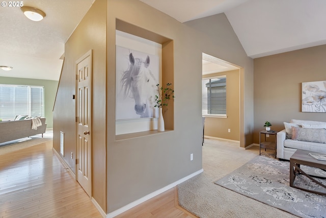 corridor featuring lofted ceiling and light hardwood / wood-style flooring