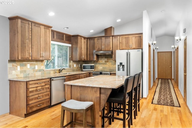 kitchen with tasteful backsplash, a center island, vaulted ceiling, and appliances with stainless steel finishes