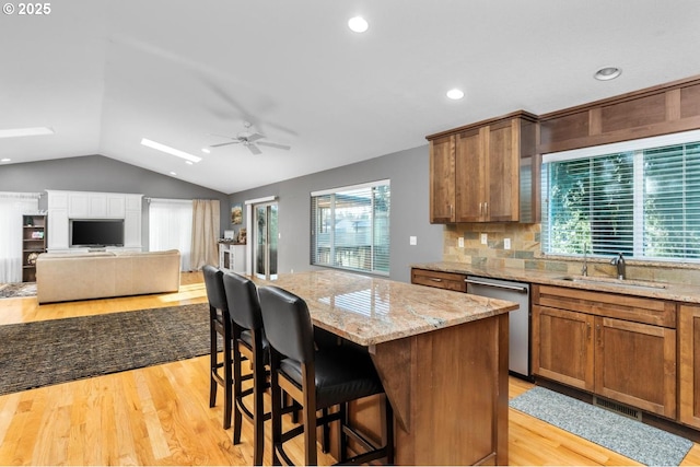 kitchen featuring a center island, tasteful backsplash, stainless steel dishwasher, and light hardwood / wood-style floors