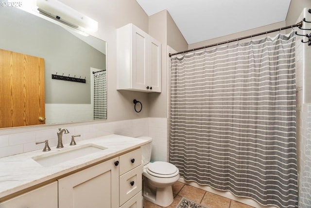 bathroom featuring tile patterned floors, vanity, toilet, and tile walls