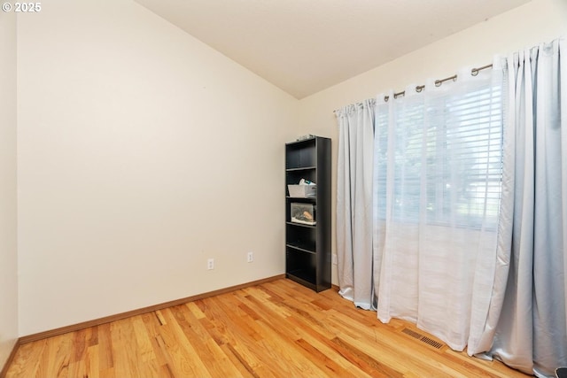 unfurnished room with hardwood / wood-style floors and lofted ceiling